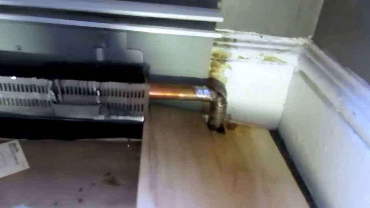 instalator układający rury podłogówki obok istniejącego grzejnika ściennego w łazience